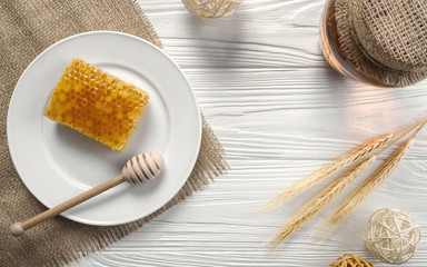 Fototapeta na wymiar Honey comb on white plate and glass jar on wooden background