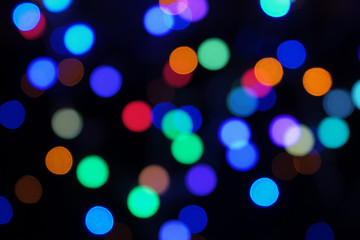 Blurred colorful bokeh lights abstract background on black. Defocused image