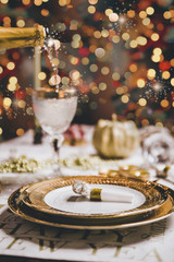 New year table setting with exclusive and luxury golden cutlery, over a tabletop with celebrations world " new year" against a background with great light and bokeh.