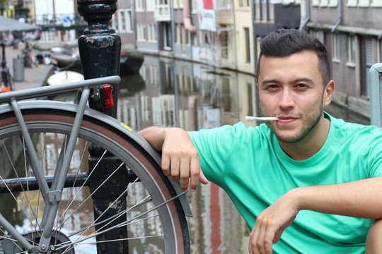 Ethnic man smiling in Amsterdam while holding joint