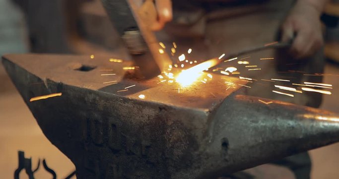 Blacksmith is hammering the iron. Anvil close up. Workplace blacksmith