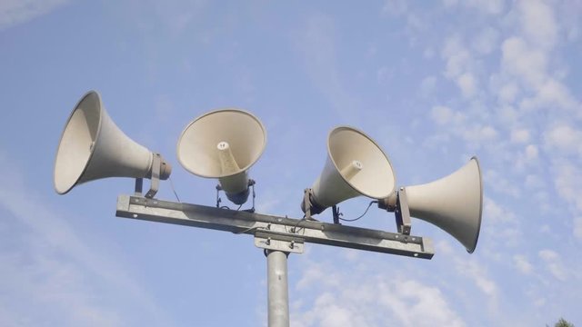 Loudspeaker warning system. System of alert for population. Sound amplifier with loudspeaker against the sky and fresh green forest.