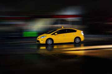 Fototapeta na wymiar Yellow electric cab in a city enviroment. Panning blur