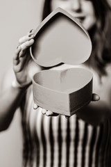 Close-up view at heart shape gift box in woman hands. Image in black and white color style