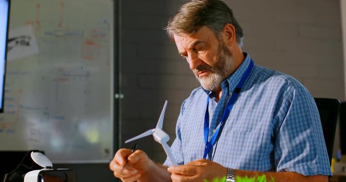 Male executive examining a windmill model 4k