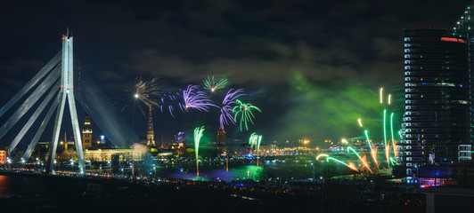 Colorful fireworks over river Daugava on Latvia's 100th birthday. Independence day celebration in Riga city with panoramic view over the old town and cable bridge. Light show in Riga city.