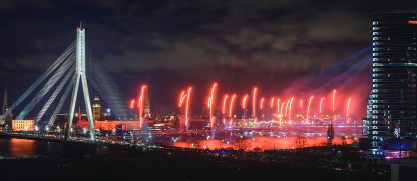 Colorful fireworks over river Daugava on Latvia's 100th birthday. Independence day celebration in Riga city with panoramic view over the old town and cable bridge. Light show in Riga city.