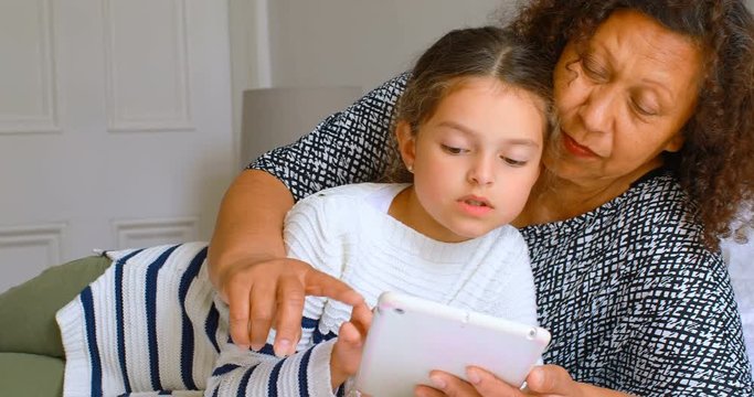 Girl using digital tablet with grandmother in bedroom 4k