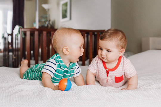 Group portrait of two white Caucasian cute adorable funny baby boys lying together on bed communicating and playing. Friendship childhood concept. Best friends forever. Children talking
