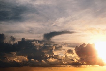 Full frame sea of dark cumulus storm clouds gathering, moving towards covering bright golden sunny sun