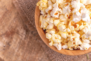Tasty salty popcorn in wooden bowl on burlap napkin