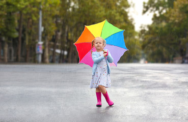 Cute little girl with umbrella in city on rainy day