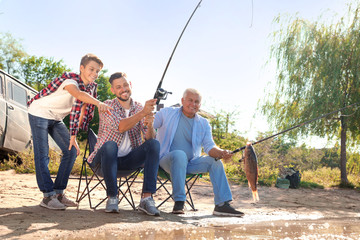 Fototapeta premium Happy family fishing together from riverside on sunny day