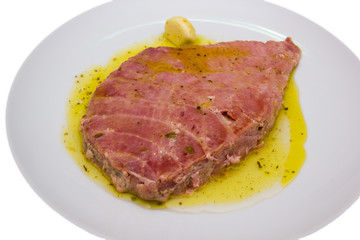 Slice of tuna on plate on a white background seen close up