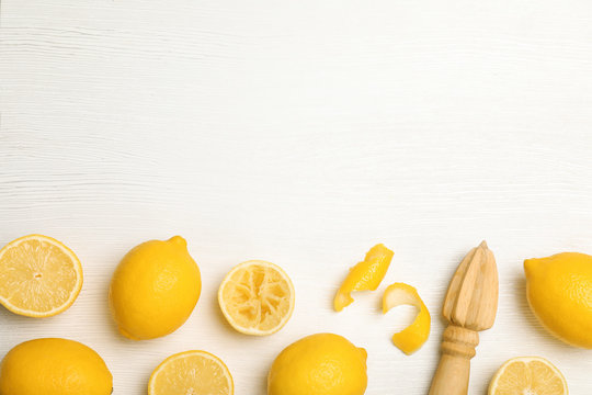 Composition with reamer and fresh lemons on white wooden background, top view. Space for text