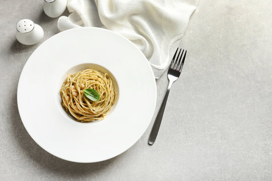 Plate of delicious basil pesto pasta served for dinner on table, flat lay with space for text
