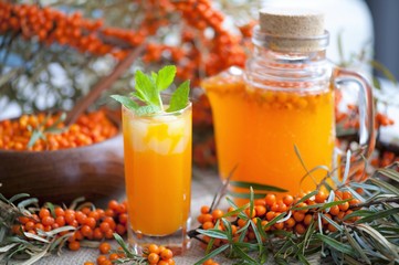 Homemade buckthorn soft drink in a glass and ripe sea buckthorn berries on the table. Healthy and diet food. Seabuckthorn, a spoon with berries and a glass of juice.