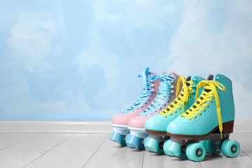 Vintage roller skates on floor near color wall. Space for text