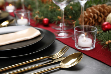 Christmas table setting with plates, cutlery, napkin and festive decor on grey background, closeup