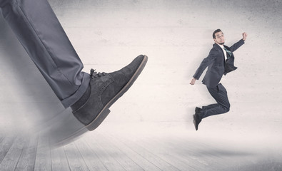 Big foot in a black shoe fire small, young, businessman who is flying away in the space
