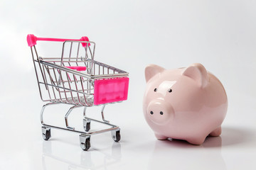 Small supermarket grocery push cart for shopping with piggy bank isolated on white background. Sale...