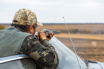 Hunter with a hat and a gun in search of prey in the steppe	