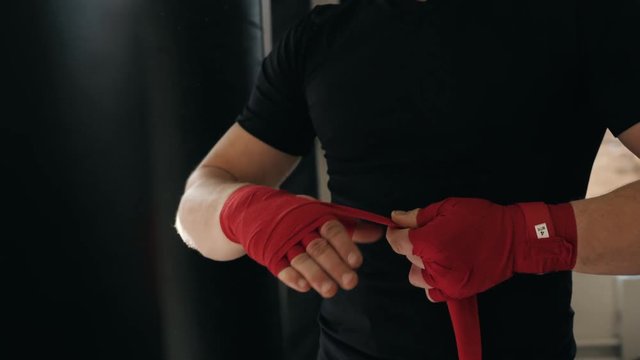 boxer adult man wrapping his hands in red boxing tape before a fight close up macro mma fighter
