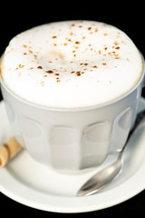 Delicious Cappuccino served with chocolate hazelnut wafer roll isolated black background