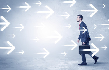 Obraz premium Businessman walking with arrows on the background and briefcase on his hand 