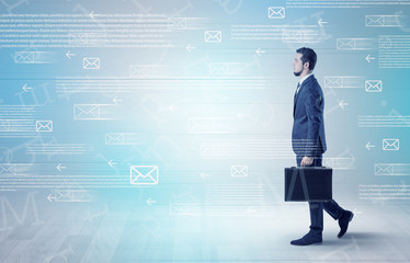 Handsome businessman walking in suit with briefcase on his hand and online communication concept around
