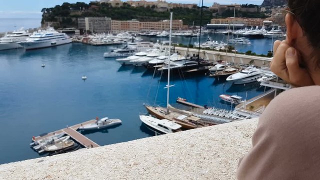 Pretty woman observing yachts in port, dreaming of oligarch and rich life