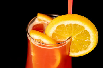 Alcoholic cocktail with lemons inside and lemon wedge on the glass with straw