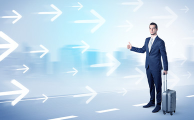 Young businessman hitchhiking near the city with arrows around concept