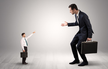 Small businessman in shirt pointing to an afraid businessman
