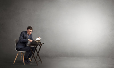 Man working hard on a typewriter in an empty space
