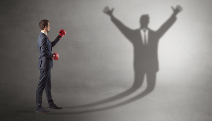 Businessman with boxing gloves fighting with disarmed businessman shadow
