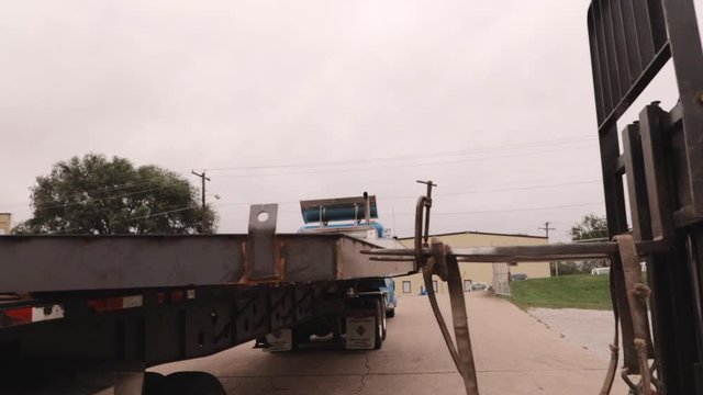 Zooming into CAT Forklift with winch straps and flatbed trailer in slow motion.