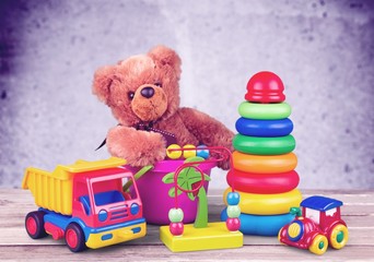 Toys collection and teddy bear on wooden desk in room