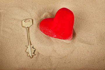 Fototapeta premium Key next to a heart in the sand