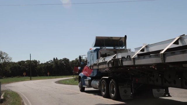 Slow motion panning side view of blue heavy duty loaded oversize truck.