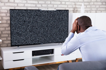 Man Sitting Near Television Showing No Signal