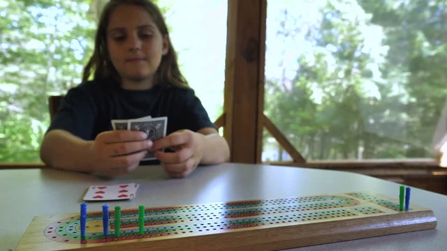 Child playing a card and moving a cribbage peg.