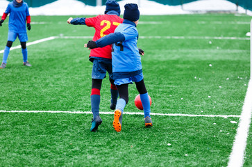 Boys  in red and blue sportswear kicking soccer ball on green grass field. youth football game. Children sport competition, kids plays outdoor, winter activities, training