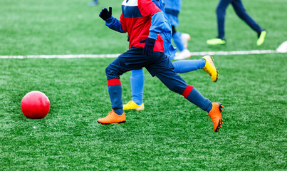 Boys  in red and blue sportswear kicking soccer ball on green grass field. youth football game....