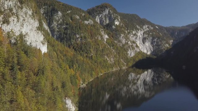 Aerial, drone shot, above the water, around forest, in a valley, mountains reflecting from a lake, on a sunny and foggy morning, at Toplitzsee, near grundlsee, in Liezen, Austria