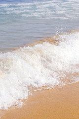 
Ocean wave with bubble hits the sandy beach