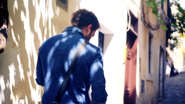 Young Handsome Man Listening Music with a Mobile Phone on the Streets of Rome Italy. 4k 25p 1/50s
