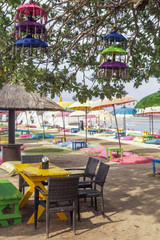 Colorful bohemian style beach club, sandy beach with tables, chairs and colorful umbrellas