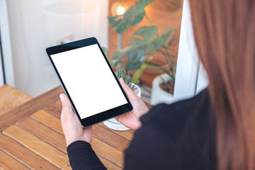 Mockup image of a woman holding and looking at black tablet pc with blank white screen