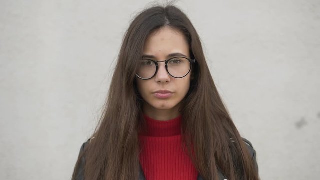 Slow motion portrait of beautiful trendy young european woman looking at camera running hand through hair enjoying urban city lifestyle. Real people concept.